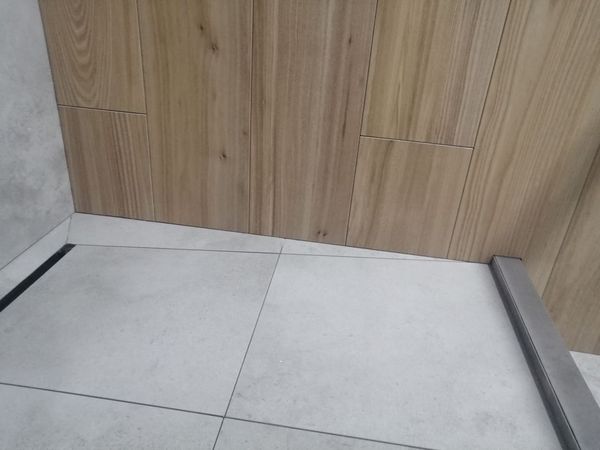 Душевой пол из светлого керамогранита с подрезкой к линейному трапу, стена из плитки под дерево